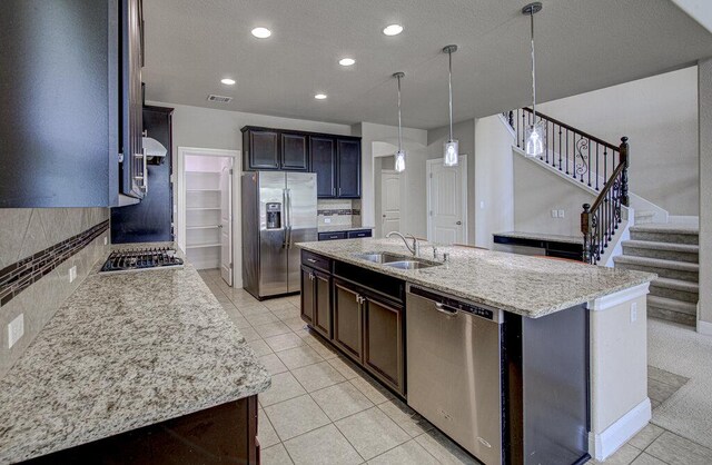 5821 Viejo Dr, Austin, TX 78738 - kitchen with appliances with stainless steel finishes, a kitchen island with sink, recessed lighting, light tile patterned floors, and backsplash