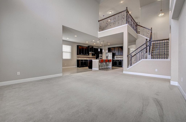 5821 Viejo Dr, Austin, TX 78738 - unfurnished living room featuring light colored carpet, a towering ceiling, stairs, and recessed lighting
