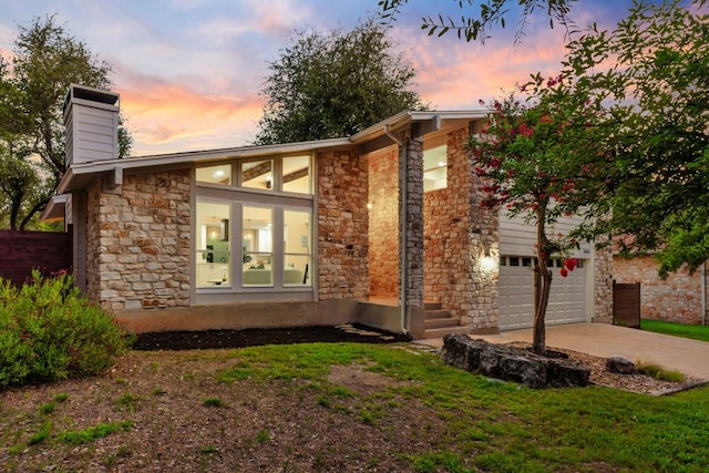 6903 Narrow Oak Trl, Austin, TX 78759 - back of property featuring stone siding, concrete driveway, a chimney, and an attached garage