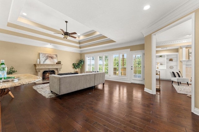 4206 River Place Blvd, Austin, TX 78730 - living room featuring a warm lit fireplace, crown molding, ceiling fan, a raised ceiling, and dark wood-type flooring