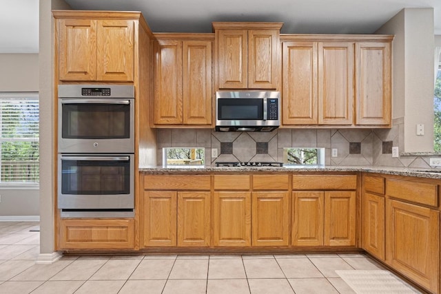 2743 Grimes Ranch Rd, Austin, TX 78732 - kitchen with appliances with stainless steel finishes, light stone counters, tasteful backsplash, and light tile patterned flooring