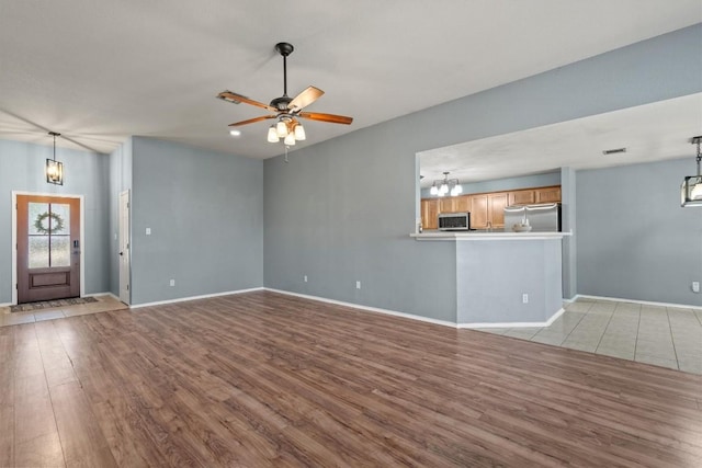 1503 Sherry Dr, Taylor, TX 76574 - unfurnished living room featuring wood finished floors, a chandelier, and ceiling fan