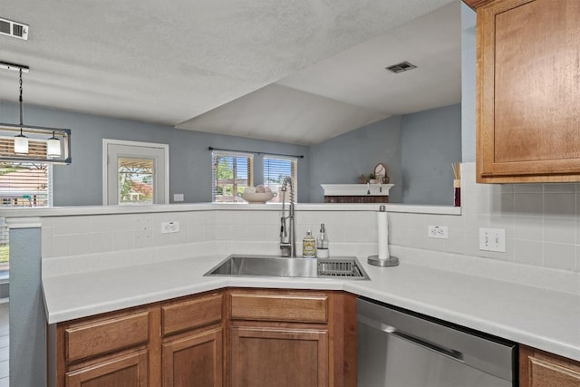 1503 Sherry Dr, Taylor, TX 76574 - kitchen with stainless steel dishwasher, light countertops, backsplash, brown cabinets, and decorative light fixtures