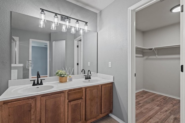 1503 Sherry Dr, Taylor, TX 76574 - full bath featuring double vanity, a walk in closet, a textured wall, and wood finished floors