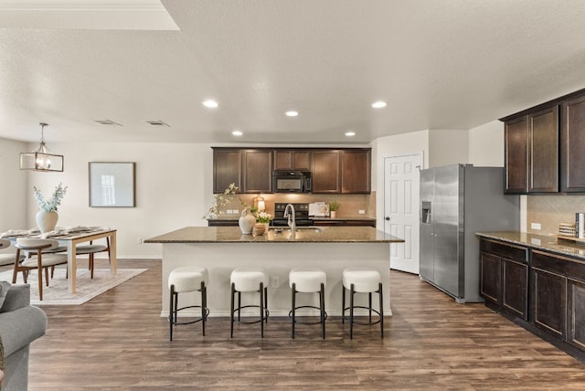 1305 Cozy Creek Dr, Temple, TX 76502 - kitchen featuring black microwave, stainless steel refrigerator with ice dispenser, a kitchen breakfast bar, recessed lighting, and dark brown cabinets
