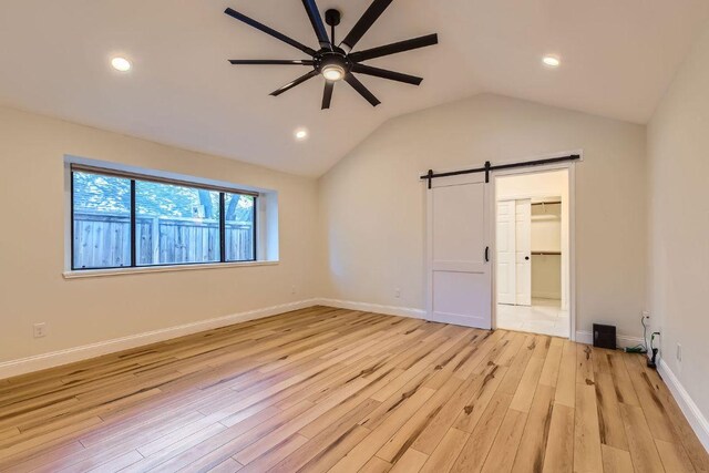 11325 Stormy Ridge Rd, Austin, TX 78739 - unfurnished bedroom featuring a barn door, light wood-type flooring, recessed lighting, lofted ceiling, and a spacious closet