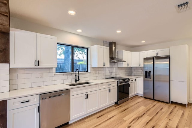 11325 Stormy Ridge Rd, Austin, TX 78739 - kitchen featuring appliances with stainless steel finishes, wall chimney exhaust hood, light wood-type flooring, white cabinetry, and light countertops