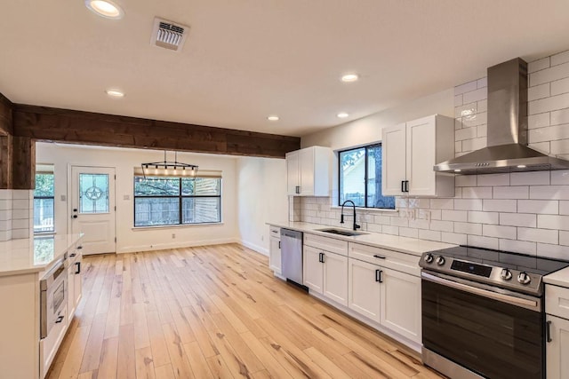 11325 Stormy Ridge Rd, Austin, TX 78739 - kitchen featuring appliances with stainless steel finishes, wall chimney range hood, light countertops, white cabinets, and recessed lighting
