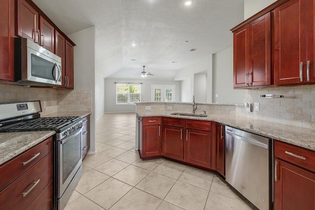 17729 Cahir Glen Cv, Pflugerville, TX 78660 - kitchen with appliances with stainless steel finishes, dark brown cabinets, a peninsula, lofted ceiling, and backsplash