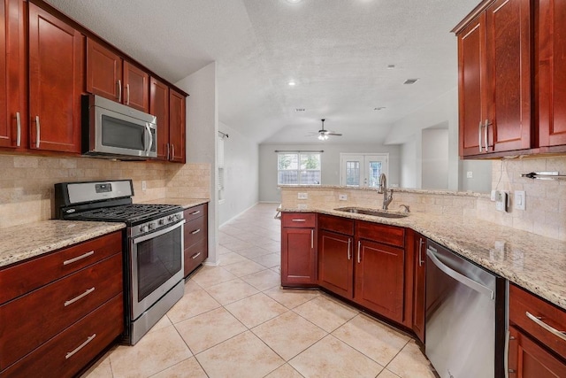 17729 Cahir Glen Cv, Pflugerville, TX 78660 - kitchen featuring stainless steel appliances, lofted ceiling, decorative backsplash, a peninsula, and light tile patterned floors