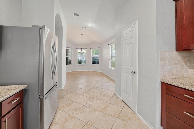 17729 Cahir Glen Cv, Pflugerville, TX 78660 - kitchen with freestanding refrigerator, light tile patterned flooring, a chandelier, lofted ceiling, and light stone countertops