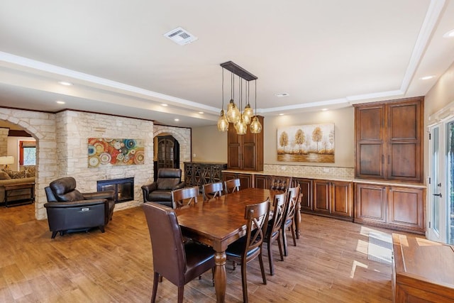 110 Lost River Rd, Georgetown, TX 78628 - dining room with a fireplace, arched walkways, light wood-style floors, a raised ceiling, and recessed lighting
