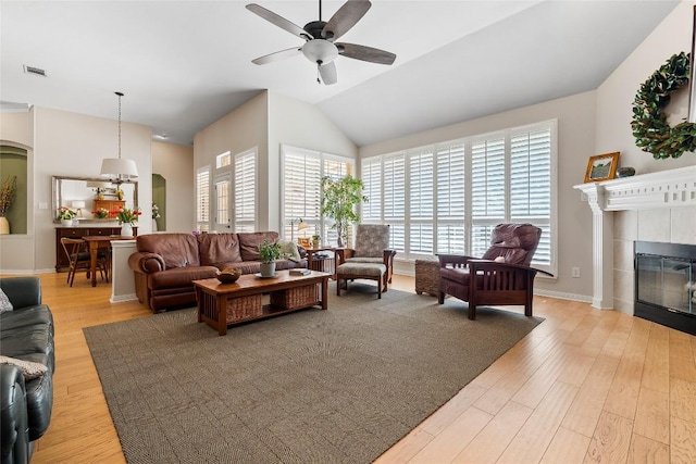 10628 Indigo Broom Loop, Austin, TX 78733 - living room featuring arched walkways, a ceiling fan, light wood-style floors, a tile fireplace, and vaulted ceiling
