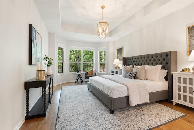 18517 Tanner Bayou Loop, Austin, TX 78738 - bedroom featuring a chandelier, wood finished floors, and a tray ceiling