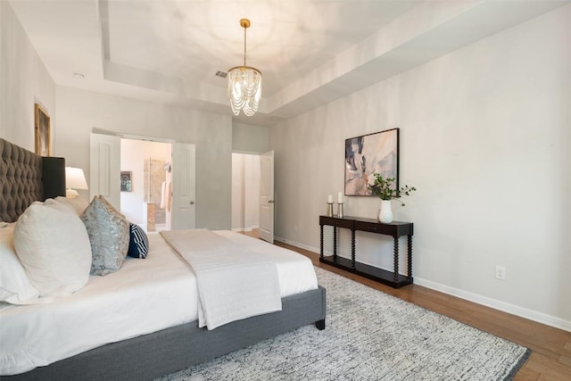 18517 Tanner Bayou Loop, Austin, TX 78738 - bedroom with wood finished floors, a tray ceiling, a chandelier, and ensuite bathroom