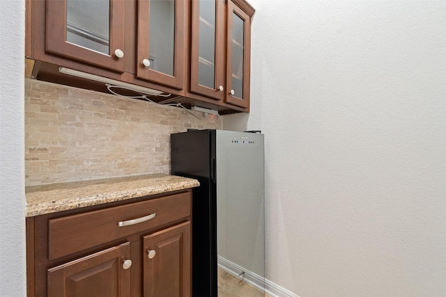 18517 Tanner Bayou Loop, Austin, TX 78738 - kitchen featuring freestanding refrigerator, glass insert cabinets, light stone counters, and tasteful backsplash