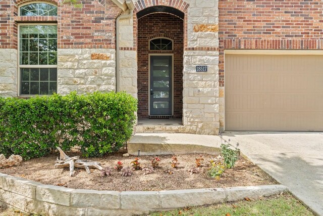 18517 Tanner Bayou Loop, Austin, TX 78738 - property entrance featuring a garage, brick siding, driveway, and stone siding