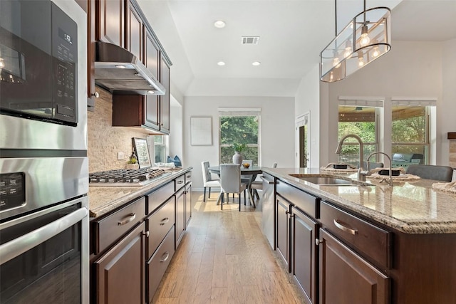 18517 Tanner Bayou Loop, Austin, TX 78738 - kitchen with stainless steel appliances, under cabinet range hood, light wood-style flooring, light stone countertops, and backsplash