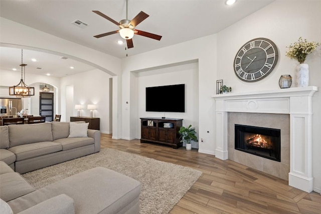 22300 Chipotle Pass, Spicewood, TX 78669 - living room with ceiling fan, recessed lighting, wood finished floors, arched walkways, and a tile fireplace