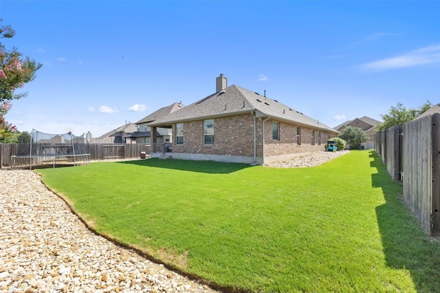 22300 Chipotle Pass, Spicewood, TX 78669 - rear view of house with a trampoline, brick siding, a chimney, and a fenced backyard