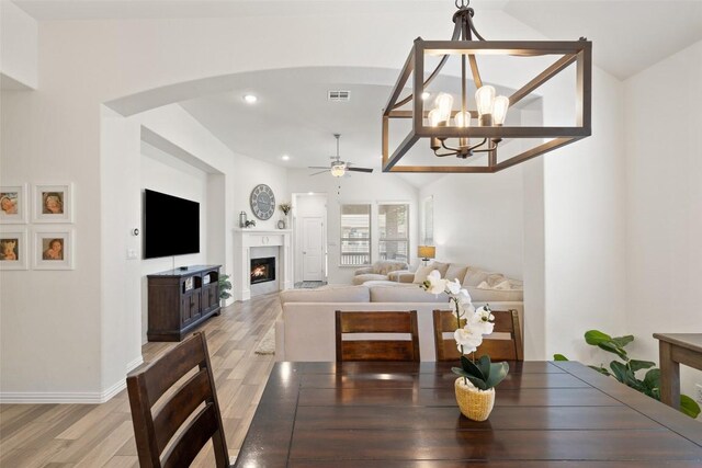 22300 Chipotle Pass, Spicewood, TX 78669 - dining room with arched walkways, a ceiling fan, light wood-style flooring, a lit fireplace, and recessed lighting