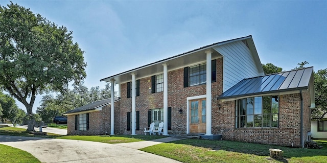 608 Sombrero Dr, Horseshoe Bay, TX 78657 - greek revival inspired property featuring a standing seam roof, a front lawn, a metal roof, and brick siding