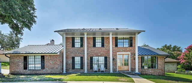 608 Sombrero Dr, Horseshoe Bay, TX 78657 - neoclassical / greek revival house featuring a standing seam roof, a front yard, brick siding, and a metal roof