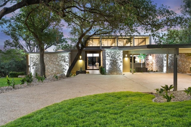 821 Malabar St, Austin, TX 78734 - mid-century modern home featuring stone siding, a front yard, an attached carport, and concrete driveway