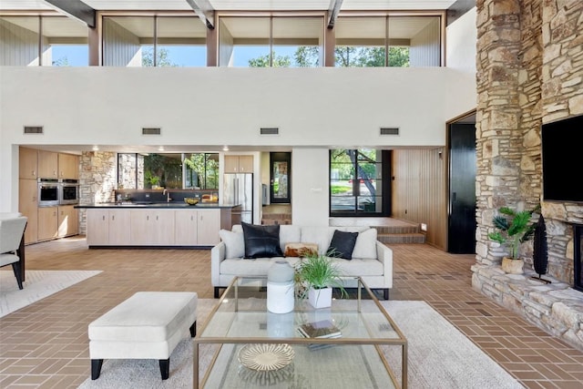 821 Malabar St, Austin, TX 78734 - living area with a fireplace, a high ceiling, brick flooring, and beamed ceiling