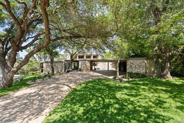 821 Malabar St, Austin, TX 78734 - mid-century modern home featuring stone siding, concrete driveway, a front lawn, and an attached carport