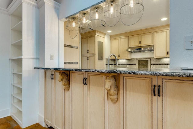 10701 Glass Mountain Trl, Austin, TX 78750 - kitchen with under cabinet range hood, dark stone counters, decorative backsplash, light brown cabinets, and recessed lighting
