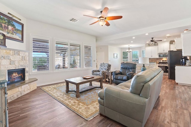 30112 Twin Creek Dr, Georgetown, TX 78626 - living area with a ceiling fan, a stone fireplace, wood finished floors, recessed lighting, and a chandelier