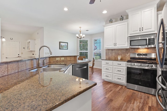 30112 Twin Creek Dr, Georgetown, TX 78626 - kitchen with appliances with stainless steel finishes, a chandelier, wood finished floors, dark stone countertops, and white cabinetry