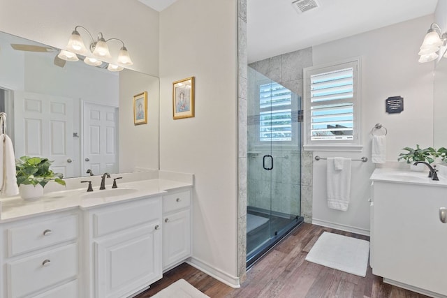 30112 Twin Creek Dr, Georgetown, TX 78626 - bathroom featuring two vanities, a stall shower, and wood finished floors