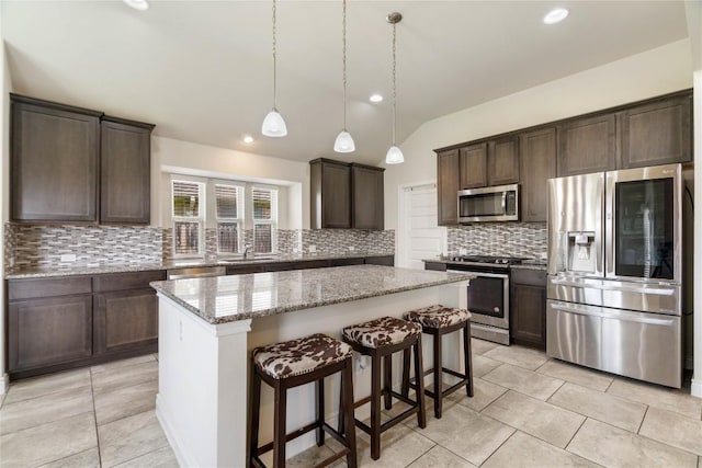 136 W Highfield St, Hutto, TX 78634 - kitchen with stainless steel appliances, a center island, dark brown cabinetry, vaulted ceiling, and backsplash