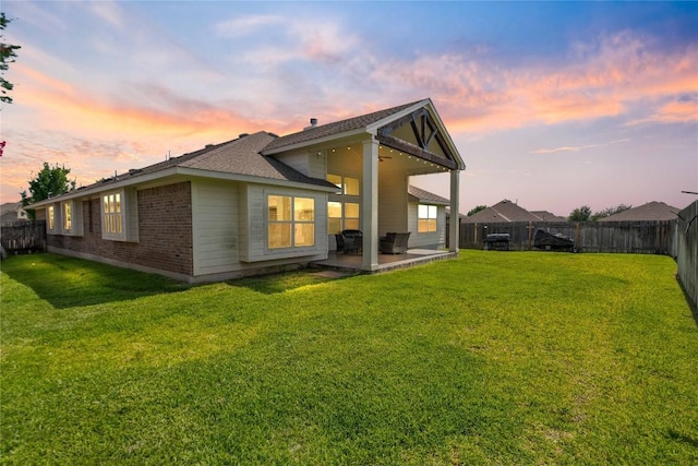 136 W Highfield St, Hutto, TX 78634 - back of house at dusk with a patio, a fenced backyard, brick siding, and a shingled roof