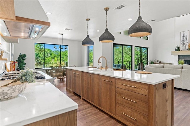 202 Hub Dr, Wimberley, TX 78676 - kitchen with brown cabinetry, exhaust hood, a large island, light countertops, and recessed lighting