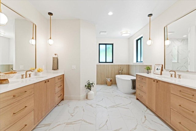 202 Hub Dr, Wimberley, TX 78676 - bathroom with two vanities, marble look tile flooring, a freestanding bath, a wainscoted wall, and recessed lighting