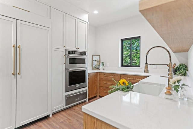 202 Hub Dr, Wimberley, TX 78676 - kitchen featuring a warming drawer, double oven, light wood finished floors, light countertops, and recessed lighting