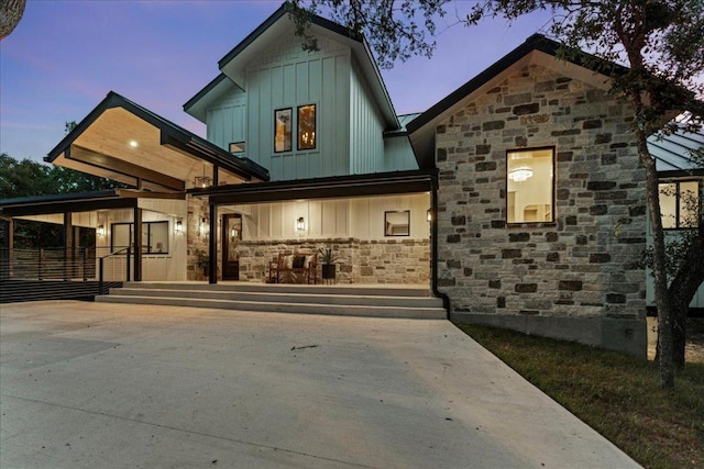 202 Hub Dr, Wimberley, TX 78676 - view of front facade with stone siding, board and batten siding, driveway, and a porch