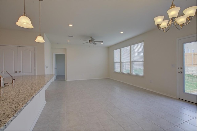 7517 Ballydawn Dr, Austin, TX 78744 - unfurnished living room featuring healthy amount of natural light, recessed lighting, light tile patterned floors, ceiling fan, and a chandelier