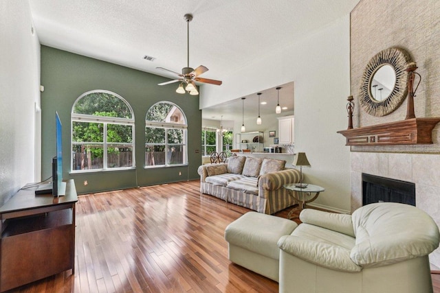 4005 Travis Country Cir, Austin, TX 78735 - living area with a ceiling fan, a tiled fireplace, wood-type flooring, high vaulted ceiling, and a textured ceiling