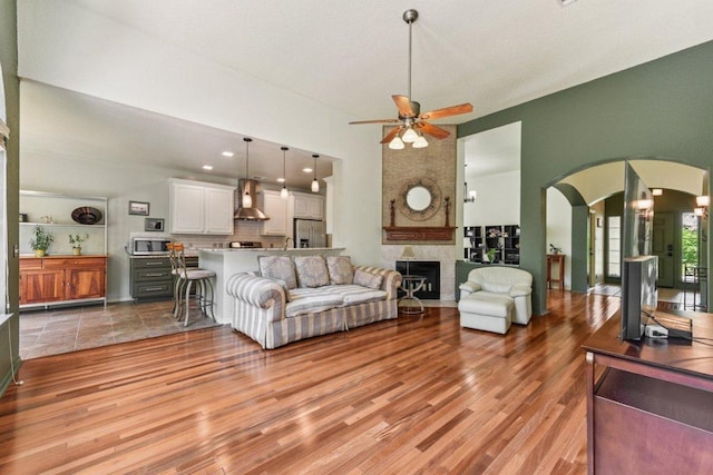 4005 Travis Country Cir, Austin, TX 78735 - living room featuring a ceiling fan, a high ceiling, arched walkways, light wood finished floors, and a large fireplace