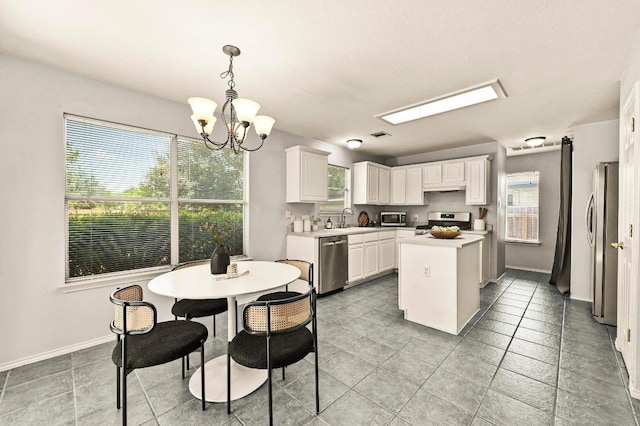 4460 Bremner Dr, Austin, TX 78749 - kitchen featuring appliances with stainless steel finishes, a chandelier, a kitchen island, light countertops, and white cabinets
