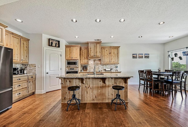 312 First Down Dash, Bertram, TX 78611 - kitchen featuring stainless steel appliances, backsplash, dark wood finished floors, light stone countertops, and a breakfast bar