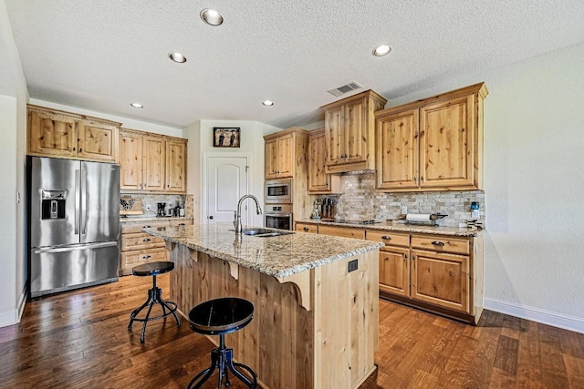 312 First Down Dash, Bertram, TX 78611 - kitchen with stainless steel appliances, dark wood finished floors, tasteful backsplash, a breakfast bar area, and light stone countertops