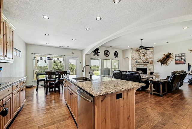 312 First Down Dash, Bertram, TX 78611 - kitchen featuring dishwasher, ceiling fan, a textured ceiling, wood finished floors, and light stone counters
