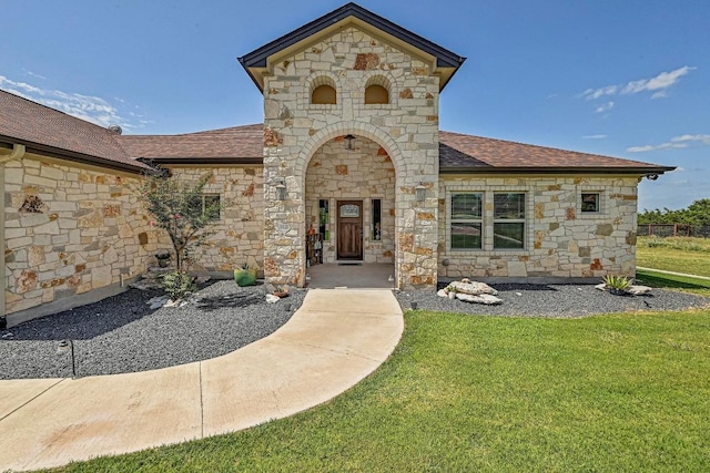312 First Down Dash, Bertram, TX 78611 - view of exterior entry with stone siding, a shingled roof, and a yard