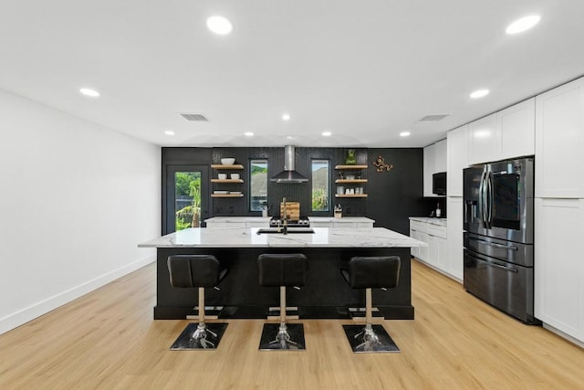 12501 Mixson Dr, Austin, TX 78732 - kitchen featuring stainless steel fridge, open shelves, wall chimney exhaust hood, light wood-style floors, and recessed lighting