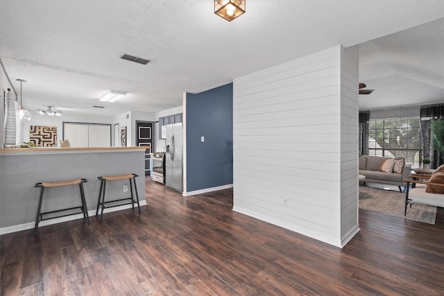 501 Battlecreek Ln, Leander, TX 78641 - kitchen featuring a textured ceiling, a breakfast bar area, dark wood-type flooring, stainless steel refrigerator with ice dispenser, and a peninsula